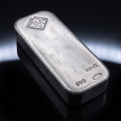 Johnson Matthey 100 oz silver bar lying flat, seen from above at an angle, with its stamps and thick side