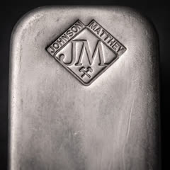 Close-up of the diamond-shaped JM stamp with the words JOHNSON MATTHEY on a vintage 100 oz silver bar